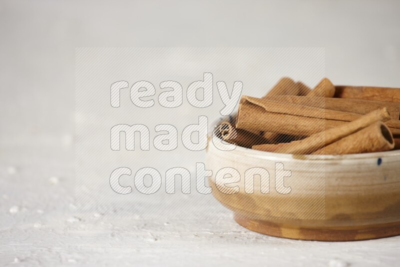 Cinnamon sticks in a ceramic bowl in different angles on white background