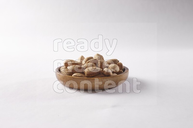 Almonds in a wooden bowl on white background