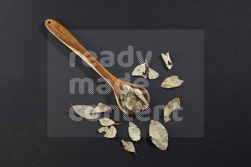 A wooden ladle filled with laurel bay on black flooring in different angles