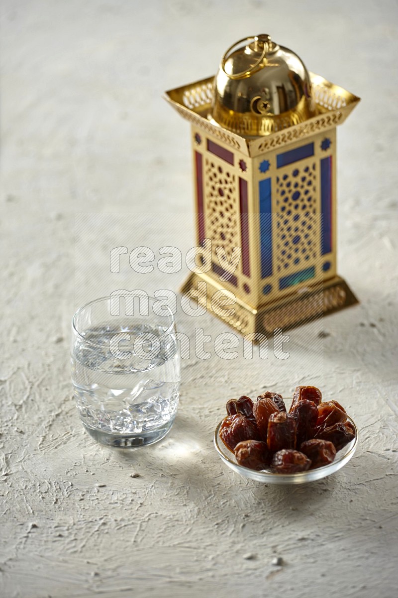 A golden lantern with different drinks, dates, nuts, prayer beads and quran on textured white background