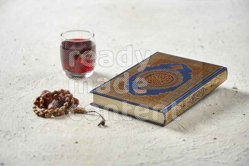 Quran with dates, prayer beads and different drinks on textured white background