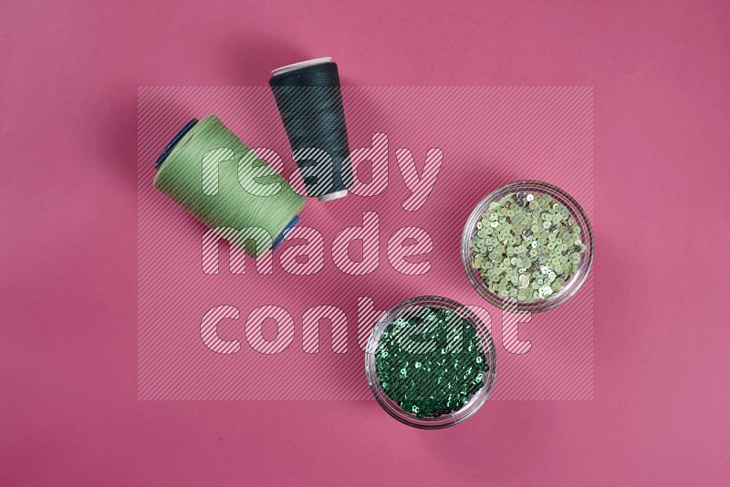 Green sewing supplies on pink background