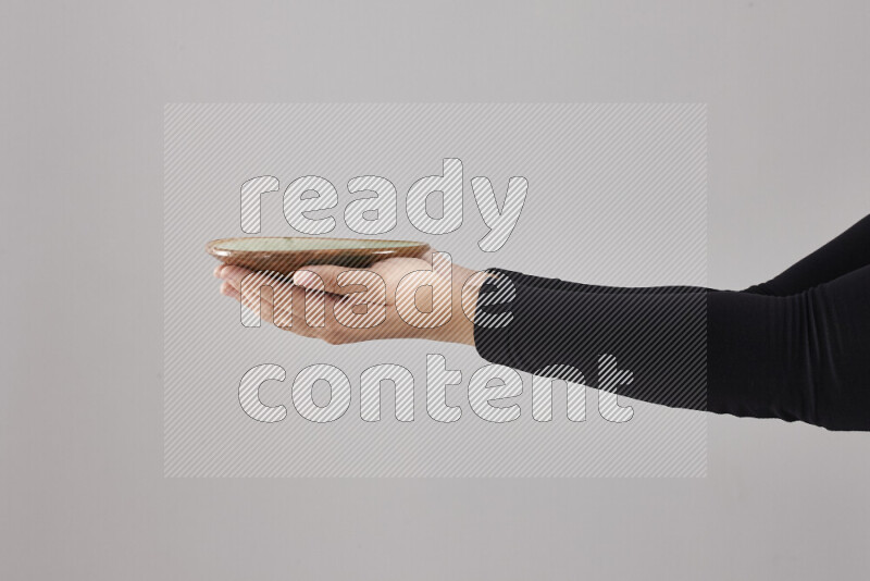 A woman in black abaya holding different pottery essentials in different positions