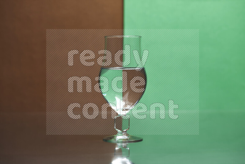 The image features a clear glassware filled with water, set against brown and green background