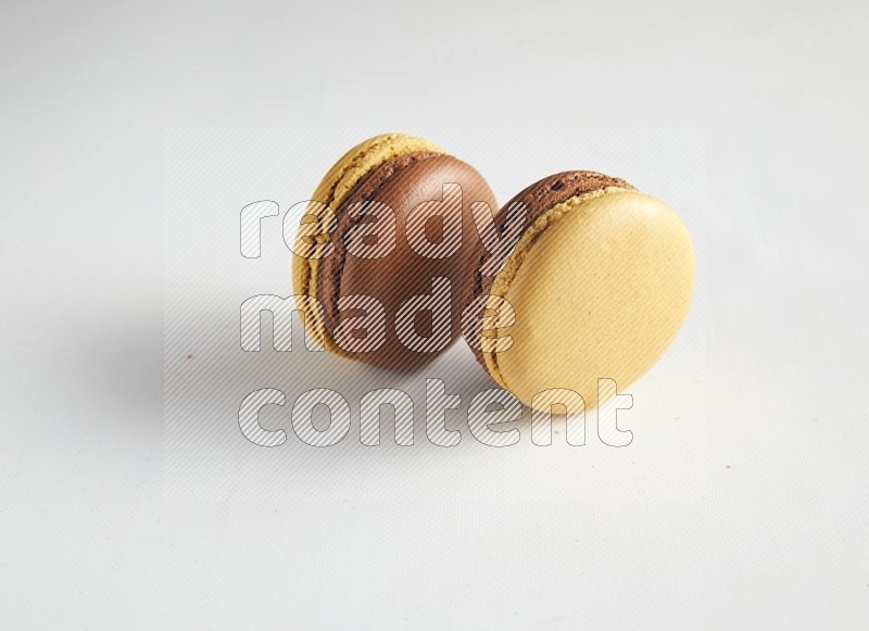 45º Shot of two Yellow and Brown Chai Latte macarons on white background