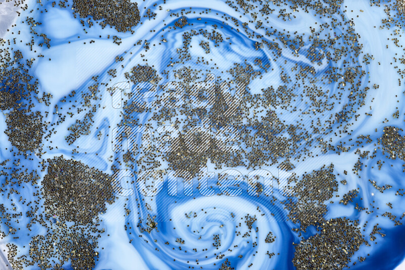 لقطة مقربة لبريق ذهبي متلألئ منتشر على خلفية من اللون الأزرق في حركات دائرية