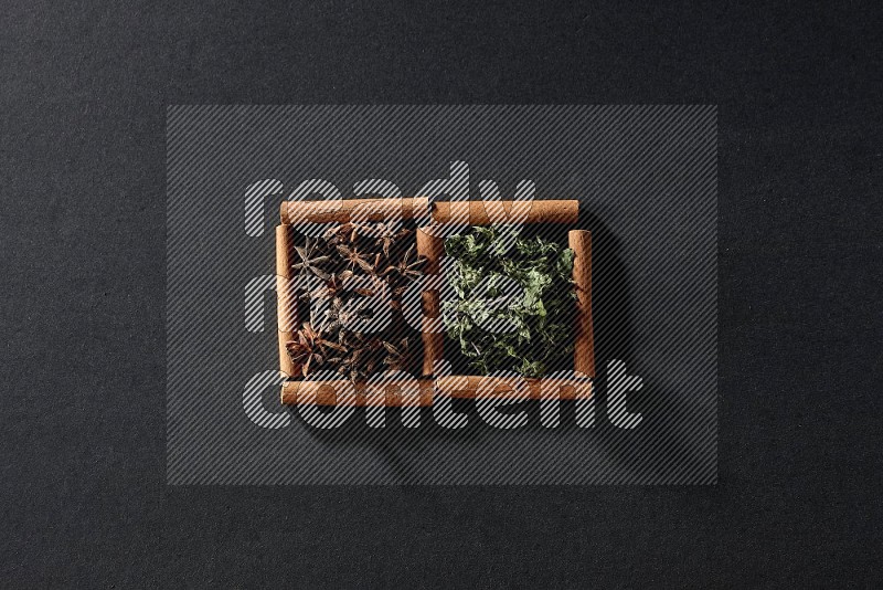2 squares of cinnamon sticks full of star anise and dried mint leaves on black flooring