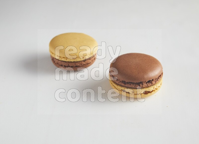 45º Shot of two Yellow and Brown Chai Latte macarons on white background