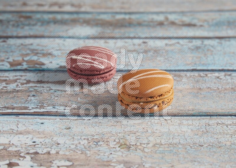 45º Shot of of two assorted Brown Irish Cream, and Red Poppy Flower macarons  on light blue background