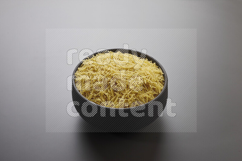 Vermicelli pasta in a pottery bowl on grey background