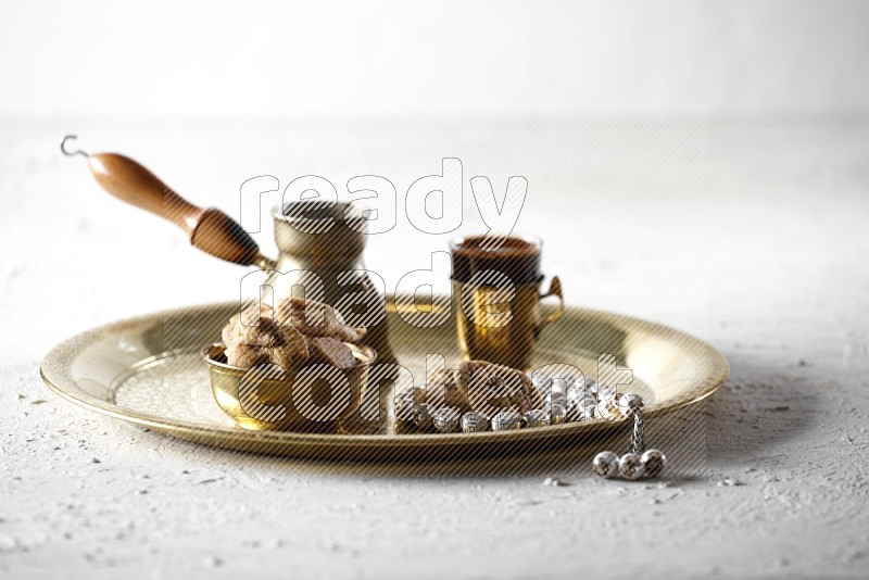 Dried figs in a metal bowl with coffee and prayer beads on a tray in a light setup