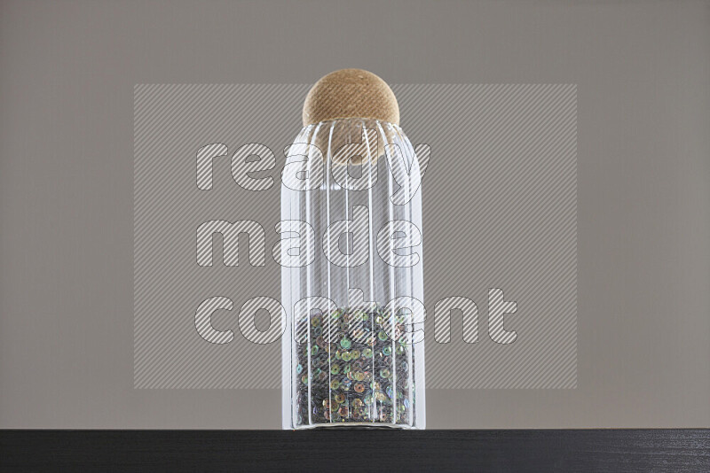 Sequins in a glass jar on black background