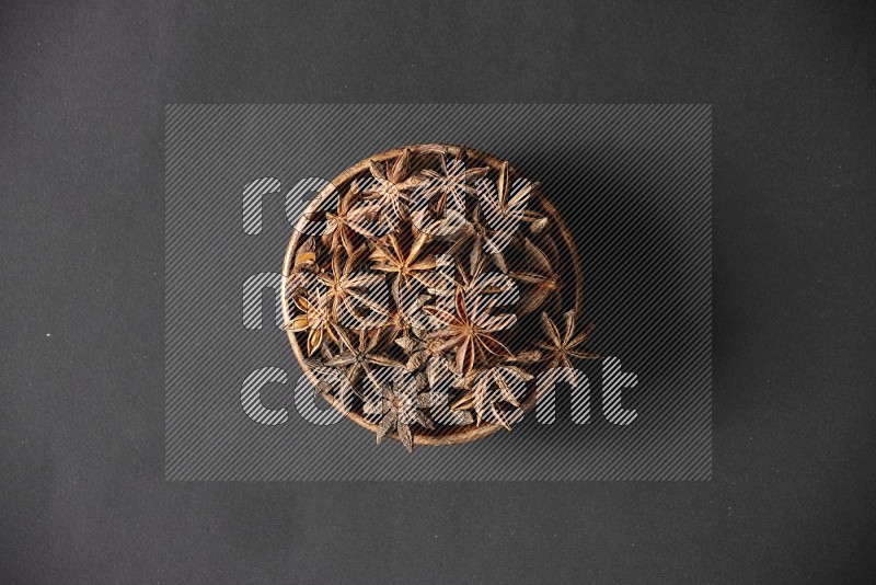 Star Anise in a wooden bowl on black flooring