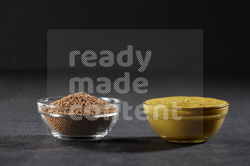 2 glass bowls, one full of mustard seeds and the other full of mustard paste on black flooring