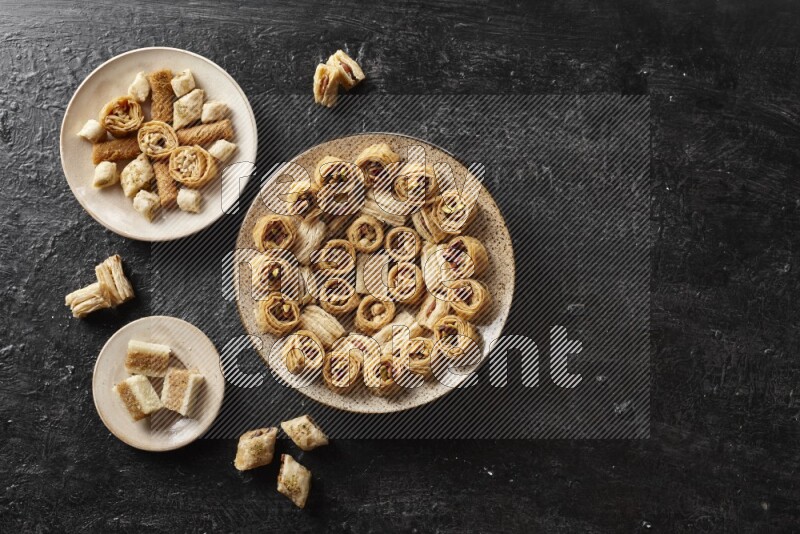 حلويات شرقية في أطباق فخارية علي خلفية سوداء خشبية