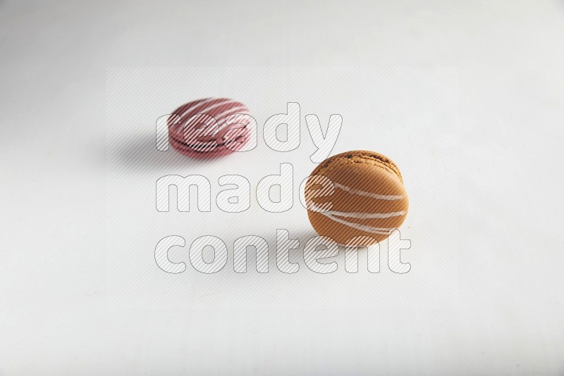 45º Shot of of two assorted Brown Irish Cream, and Red Poppy Flower macarons on white background