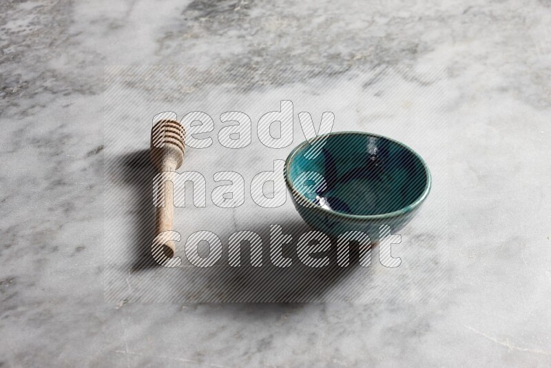 Decorative pottery bowl with wooden honey dipper on the side on grey marble background