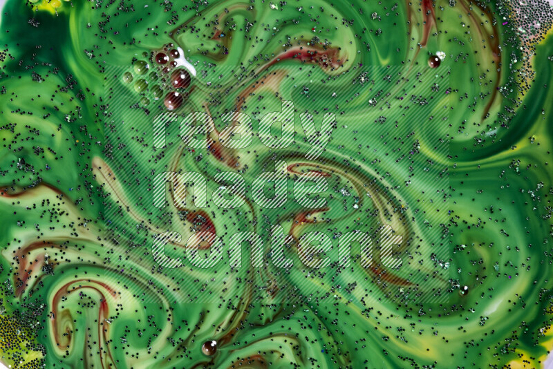 A close-up of sparkling green glitter scattered on swirling green and red background
