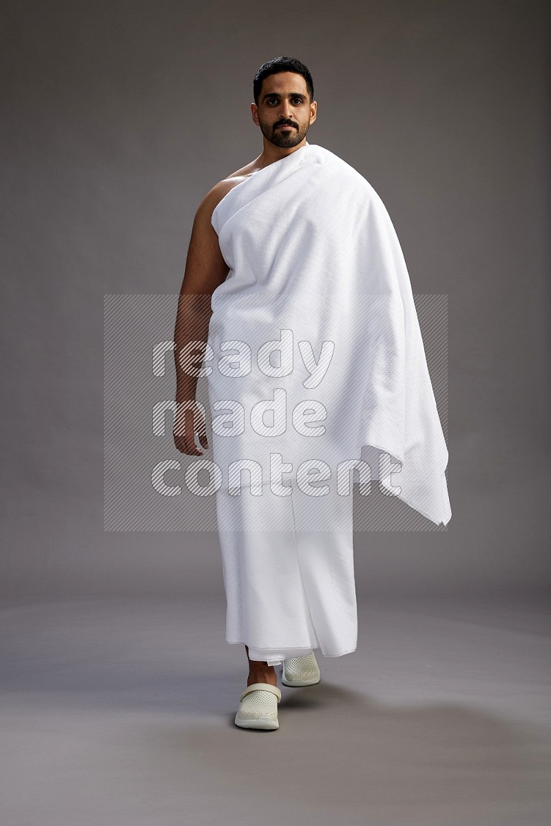 A man wearing Ehram Standing Interacting with the camera on gray background