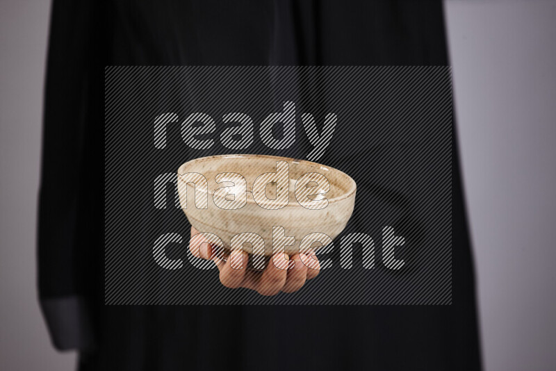 A woman in black abaya holding different pottery essentials in different positions