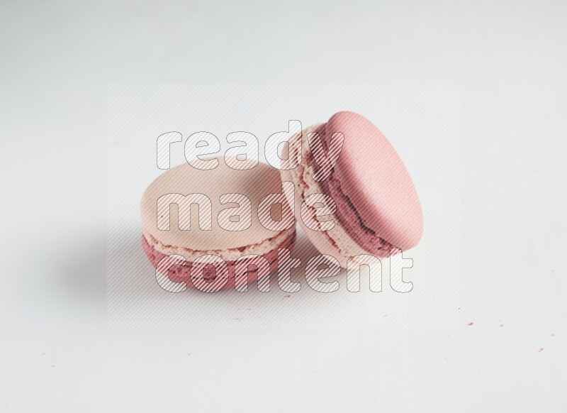45º Shot of two Pink Litchi Raspberry macarons on white background