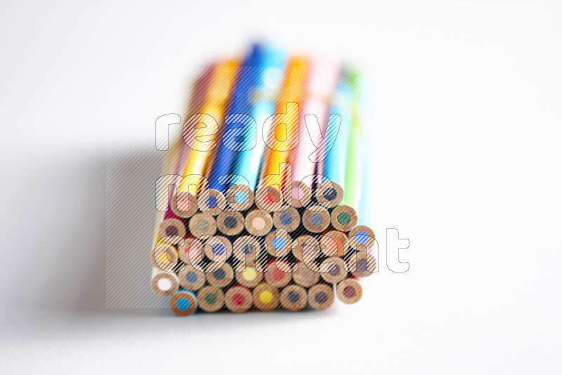 A close-up of the tips of colored pencils arranged in a bundle on white background