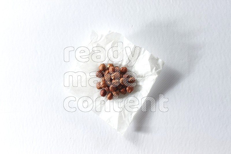 Peeled hazelnuts on a crumpled piece of paper on a white background in different angles