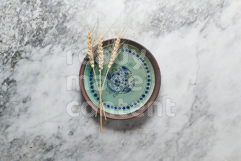 Wheat stalks on Decorative Pottery Plate on grey marble flooring, Top view