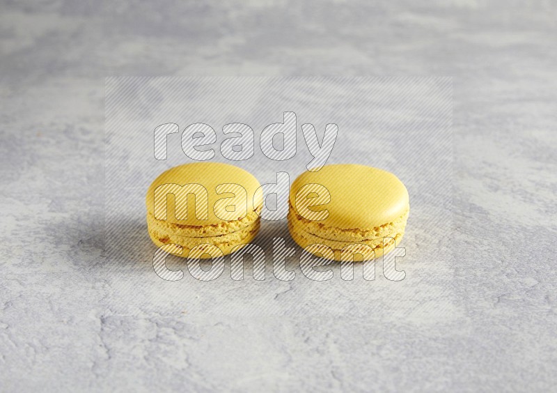 45º Shot of two Yellow Lemon macarons  on white  marble background
