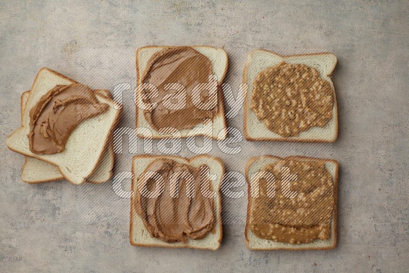 Creamy and Crunchy peanut butter on a white toast on a light blue textured background