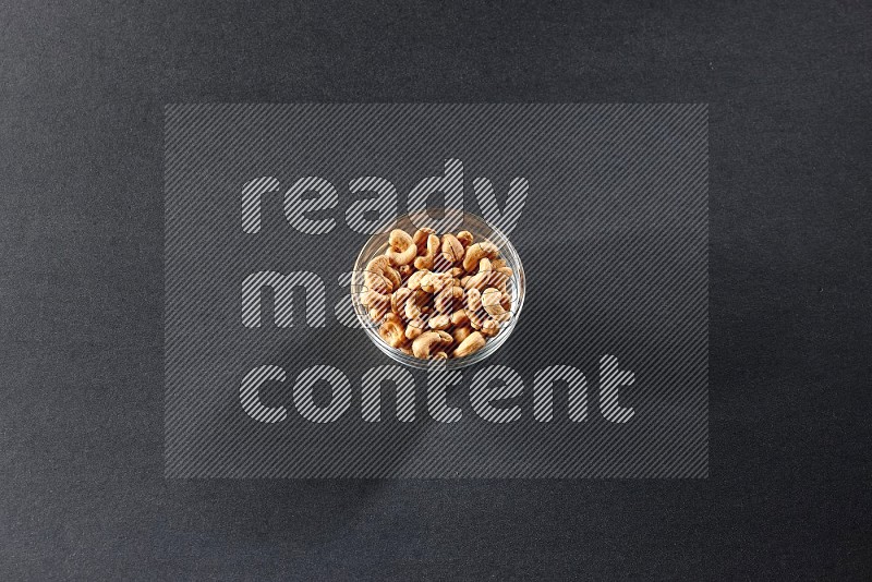 A glass bowl full of cashews on a black background in different angles