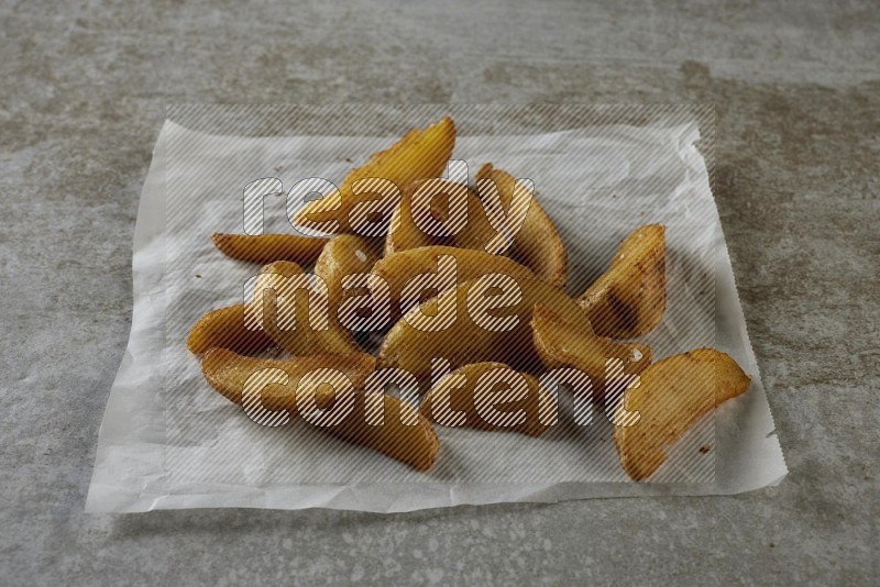 wedges potato on parchment paper on grey textured counter top