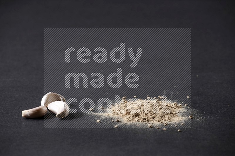 Garlic powder and garlic bulb and cloves on a black flooring in different angles