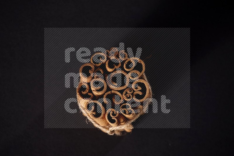 A bounded stack of cinnamon sticks on black background
