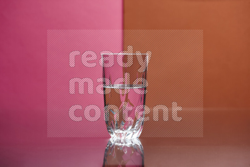 The image features a clear glassware filled with water, set against pink and dark orange background