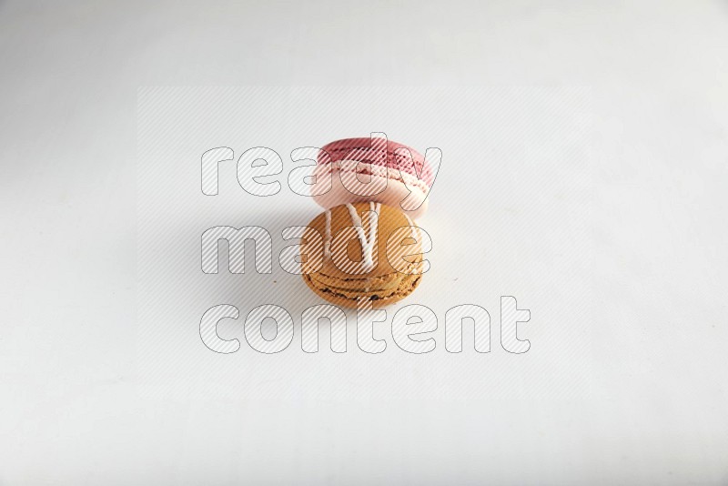 45º Shot of of two assorted Brown Irish Cream, and Pink Litchi Raspberry macarons on white background