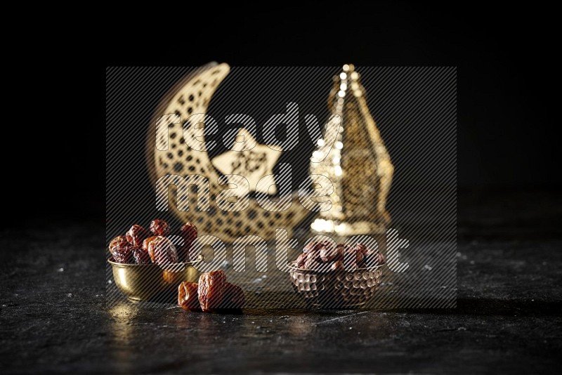 Dates in a metal bowl with hazelnuts beside golden lanterns in a dark setup