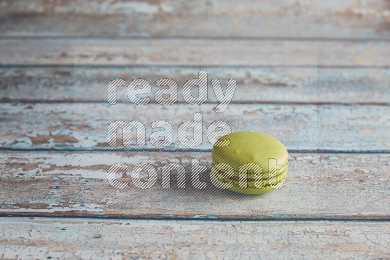 45º Shot of Green Pistachio macaron on light blue wooden background