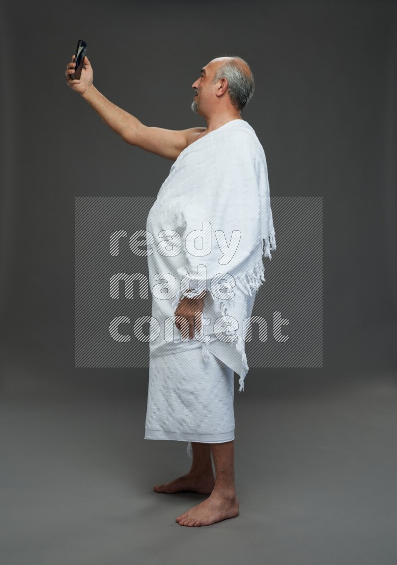 A man wearing Ehram Standing taking selfie on gray background