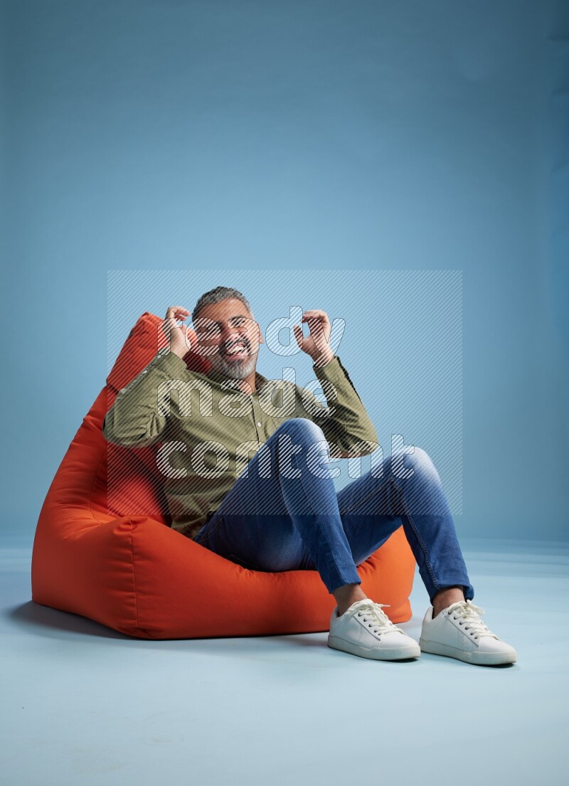 A man sitting on an orange beanbag and interacting with the camera