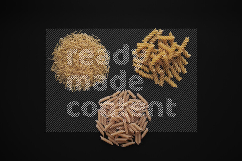 Different pasta types in bunches on black background