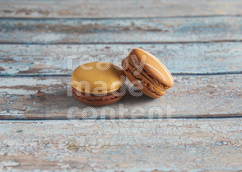 45º Shot of of two assorted Brown Irish Cream, and Yellow, and Brown Chai Latte macarons  on light blue background