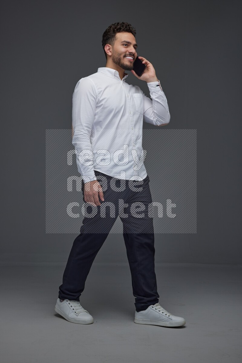 A man wearing smart casual talking in the phone eye level on a gray background