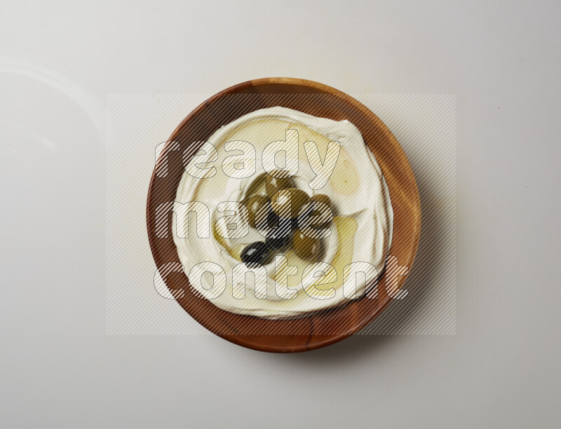 Lebnah garnished with whole olives in a wooden plate on a white background