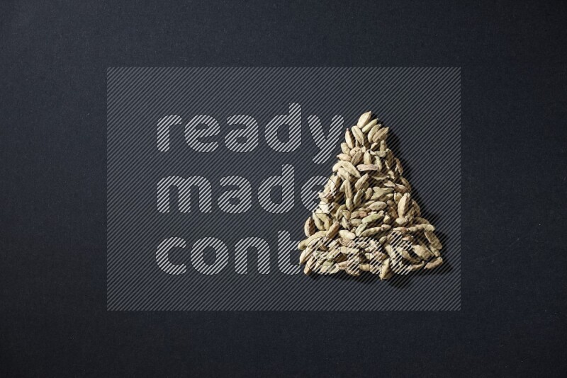 Cardamom in a triangle shape on black flooring