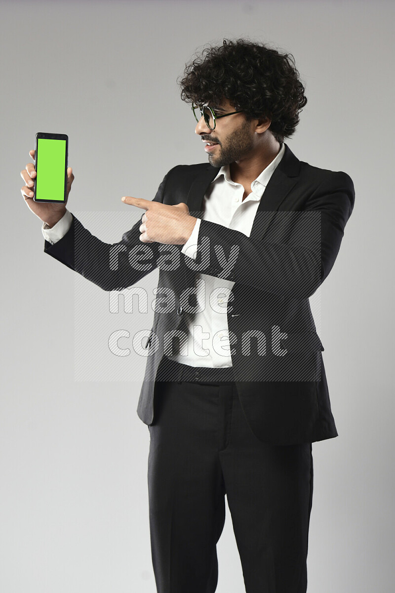 A man wearing formal standing and showing a phone screen on white background