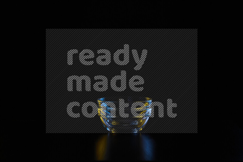 Glassware with rim light in blue and yellow against black background