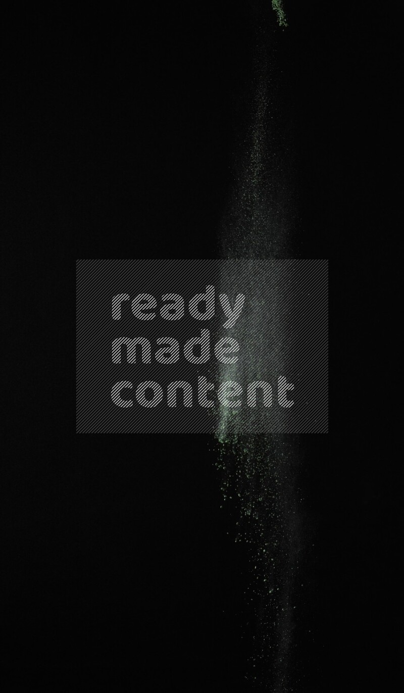 A side view of green powder explosion on black background