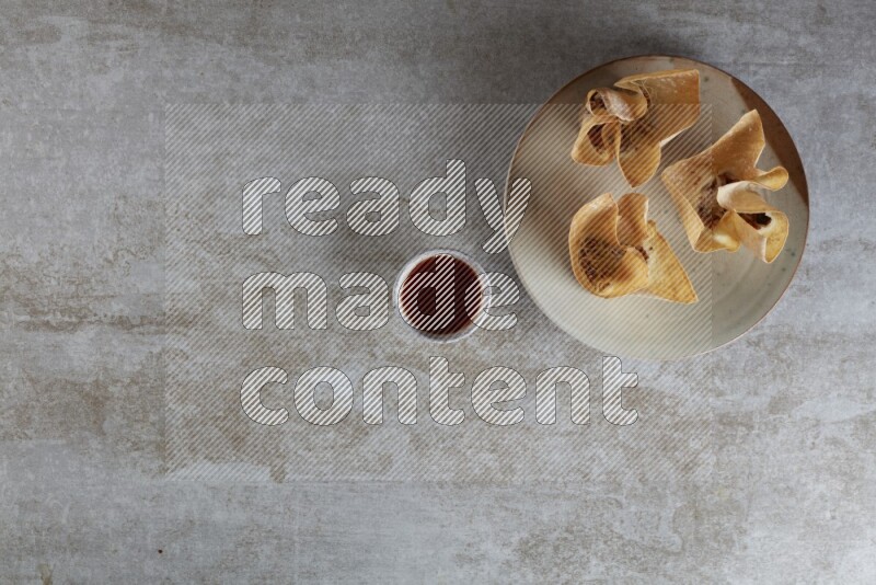 wonton cups with soy sauce ramkin on multi colored pottery on grey textured counter top