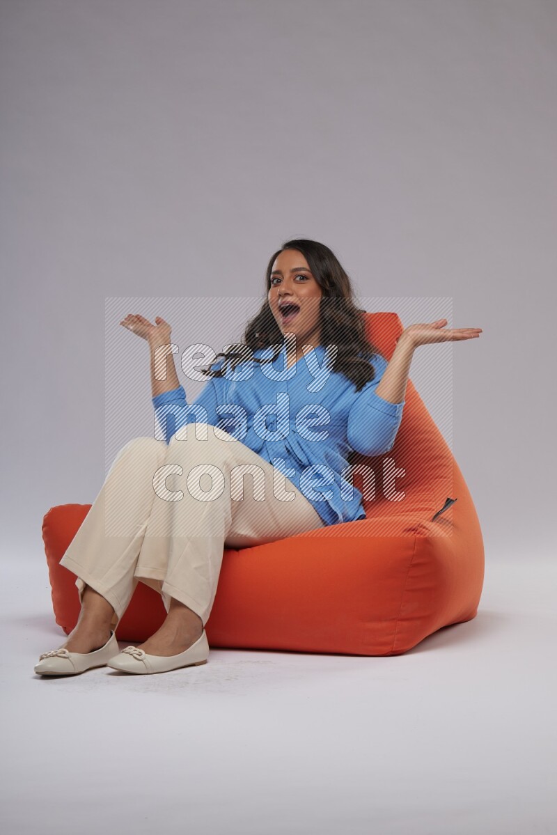 A woman sitting on an orange beanbag and interacting with the camera